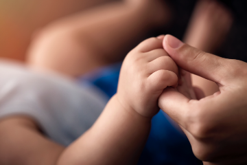 Parents holds hand with baby that suffered birth injuries.