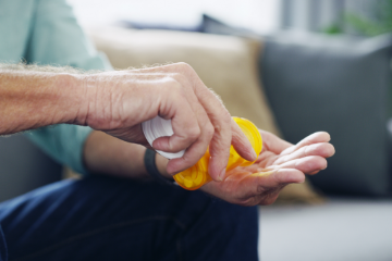 Man holds hand out while pouring medication from prescription bottle.