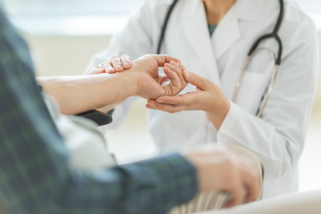 Female doctor inspects patient's wrist but fails to properly diagnose.