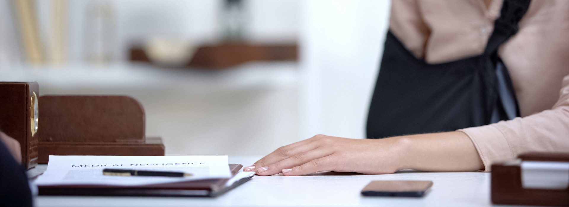 Woman in sling sits at lawyer's desk to discuss workers' compensation claim