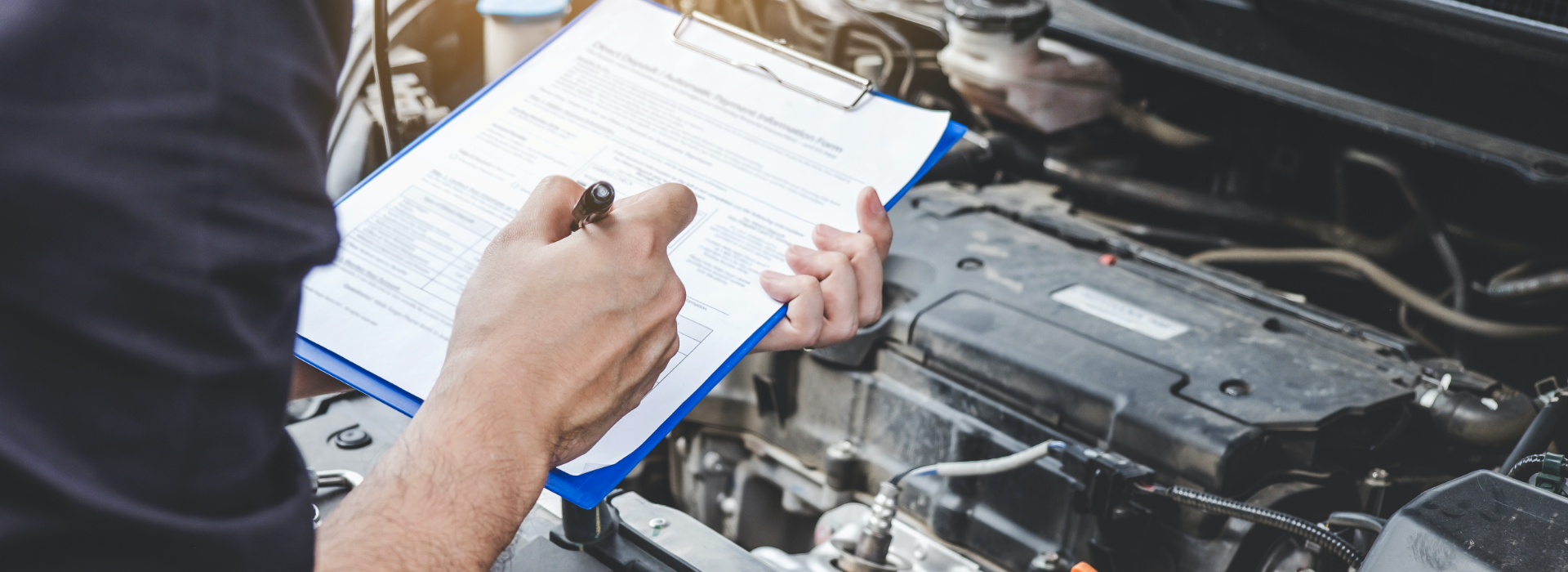 Mechanic inspects car with clipboard to note a possible automobile defect.