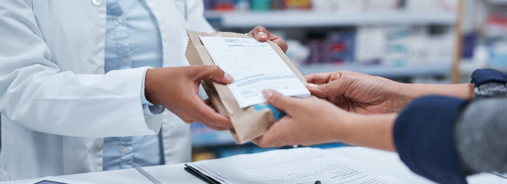 Pharmacist hands prescription pharmaceuticals to patient.