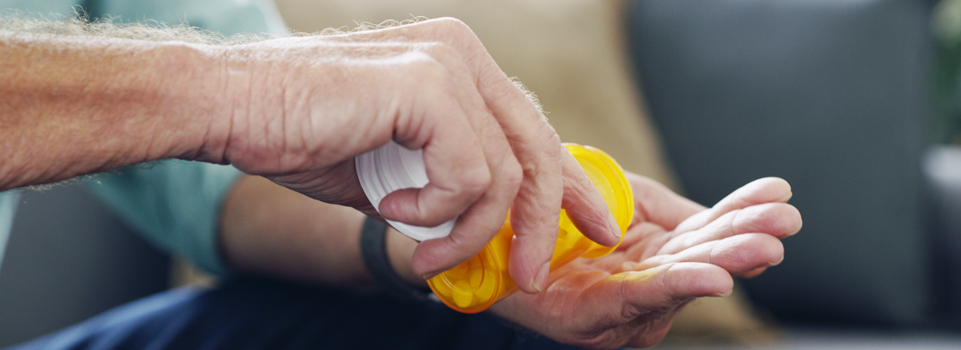 Man holds hand out while pouring medication from prescription bottle. He may need to file a medication error lawsuit.