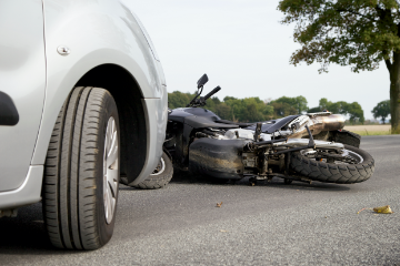 Motorcycle likes on ground after car crashes into it.