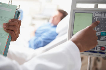 Man lying in hospital bed while doctor makes error on panel.