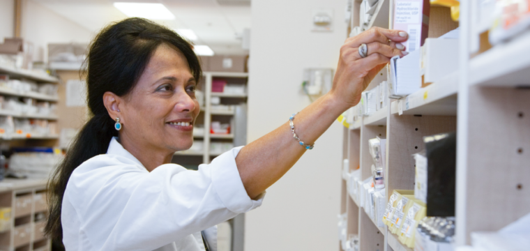 Pharmacists making a medication error as she reaches for a prescription on a shelf.