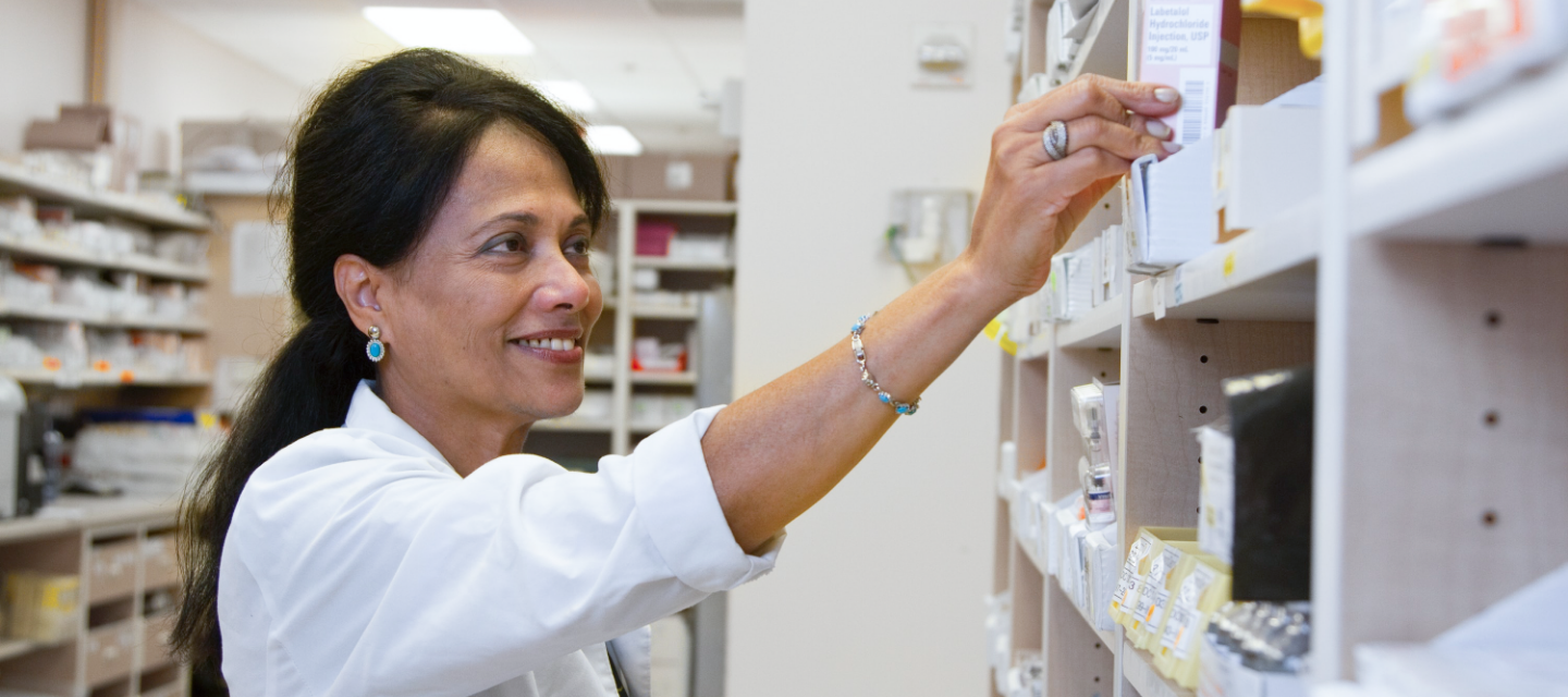 Pharmacists making a medication error as she reaches for a prescription on a shelf.