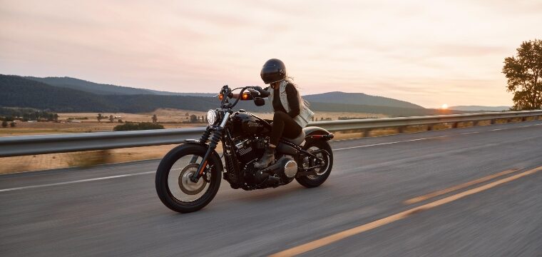 Motorcyclist riding down a two lane road at sunrise, practicing summer motorcycle safety