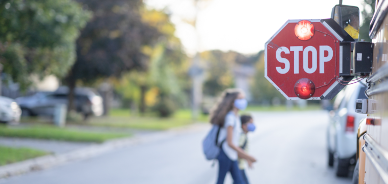Children step onto a school bus with the stop sign out for back to school safety