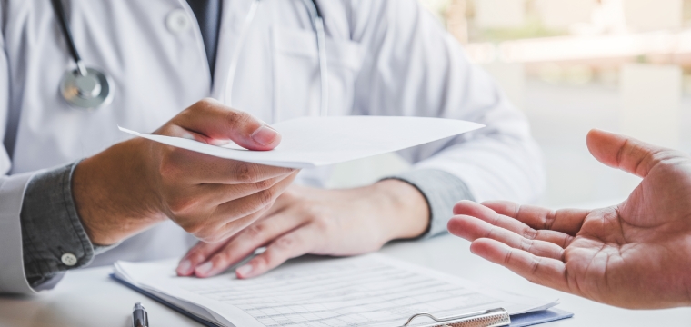 A doctor gives a misdiagnosis to a patient sitting across from him at the table.