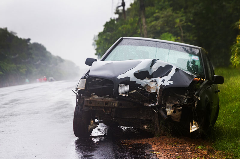 A black sedan is damaged on the side of the road after one of the most common car crashes occurred.