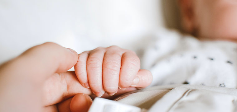 A baby holds their parent's finger after birth injury malpractice