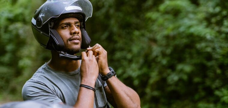 A man tightens his helmet before hitting the road on his motorcycle, in accordance with motorcycle helmet law