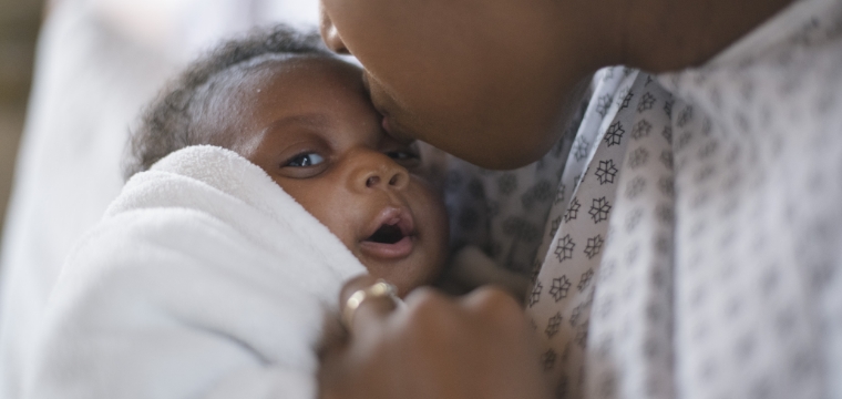 mother kissing her baby after receiving birth injury legal aid