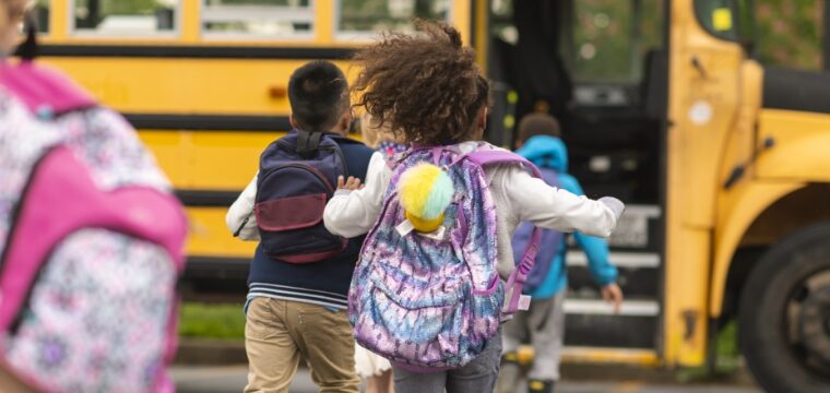 four kids running to the bus and climbing the stairs