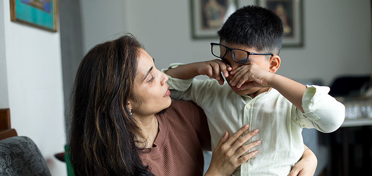 woman hugging a crying boy with glasses